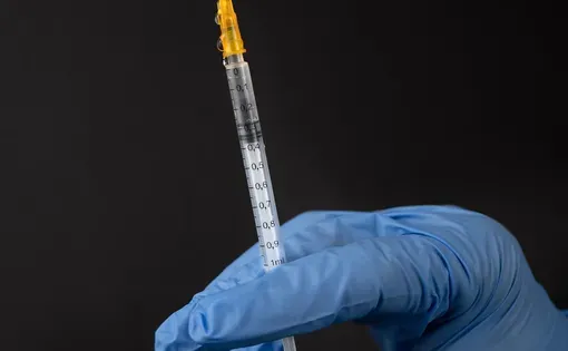 A syringe held by a gloved hand