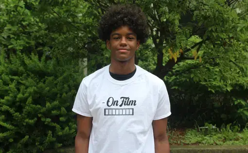 Jamar Jackson stands and smiles in a white tee shirt with trees and greenery in the background.