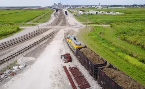 U.S. Sugar Corp.'s train transports railroad cars of sugarcane during harvest season in Clewiston, Florida to processing mill facility seen in the distance