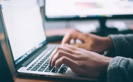 A person uses a laptop connected to a monitor