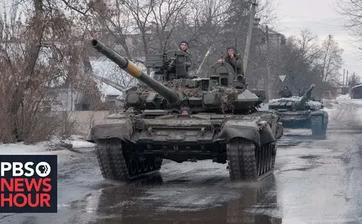 A war tank rolls through an urban area.