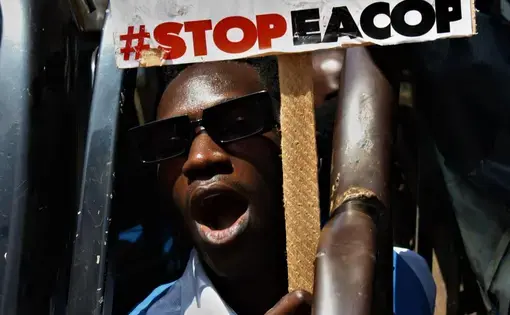 A man holds a protest sign reading "#STOPEACOP".