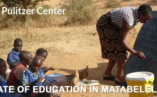 A teacher writes on a chalkboard for an outdoor class of children in Zimbabwe