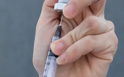 Needle extracting solution from a vial, held upside down