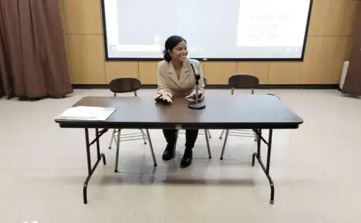 DeChalus sits at table, speaking into a mic.