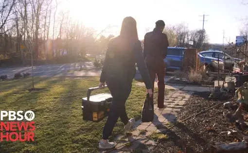 Two people walking in the sun's glare