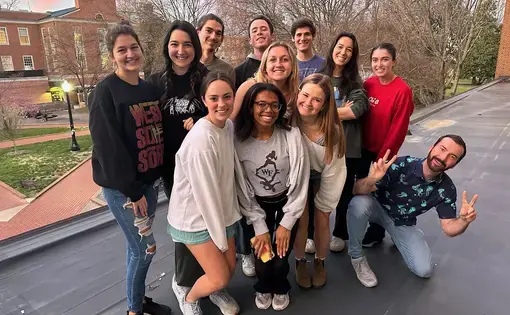 A group of people pose at dusk for a group photo