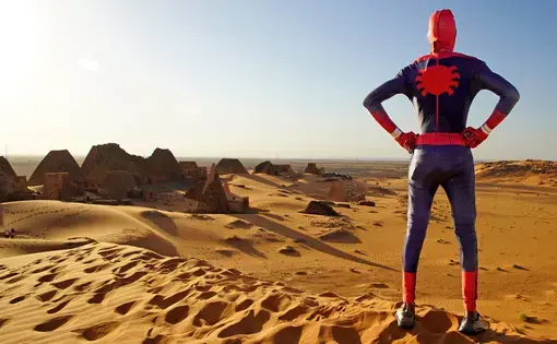 Person in Spiderman costume looks out on sand dunes