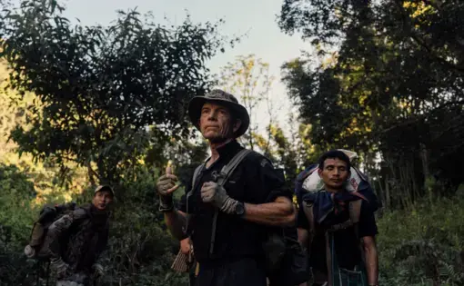 Eubank holds up his hand to signal the men behind him walking through the forest to pause.