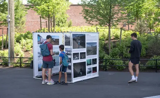 three people look at an outdoor photography exhibit