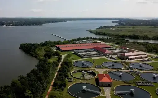 Aerial view of a sewage treatment plant on the banks of a large river.