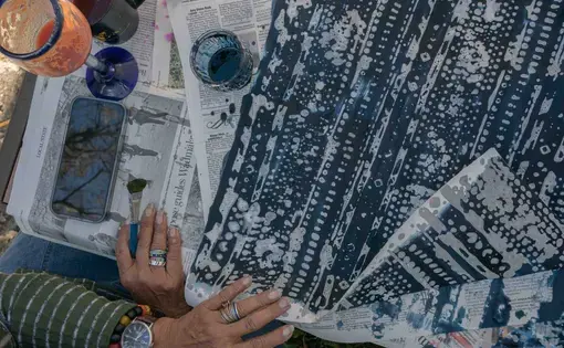 hands on a scene of fabric dyed with indigo over newsletter