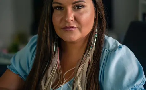 Brandi Morin portrait. Morin is sitting at a table with hands laid on a book.