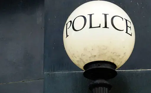A white circular street lamp with the word "POLICE" written in uppercase letters.