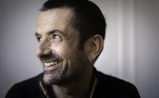 A profile headshot of a smiling man with short dark hair