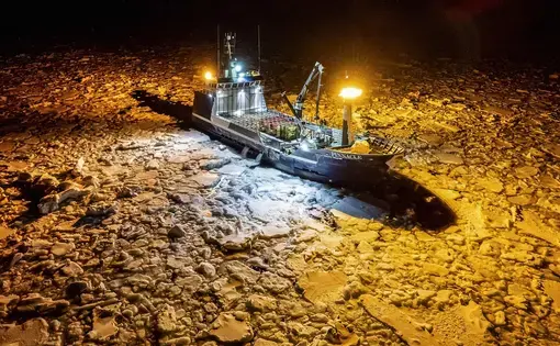 an ice crab fishing boat at night surrounded by ice