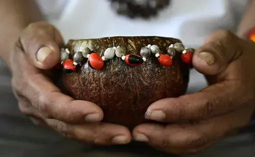 A man holding a traditional wooden bowl.