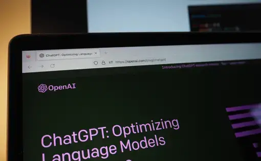 ChatGPT Chat artificial intelligence chatbot developed by Open AI is displayed with "hello world" code on a Macbook screen with a Monitor.