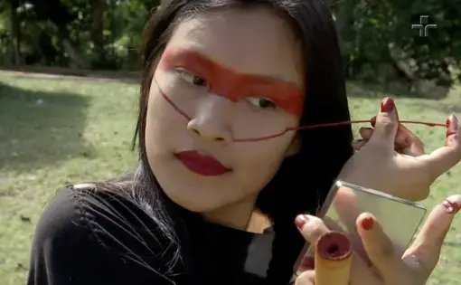 A young girl painting her face red.