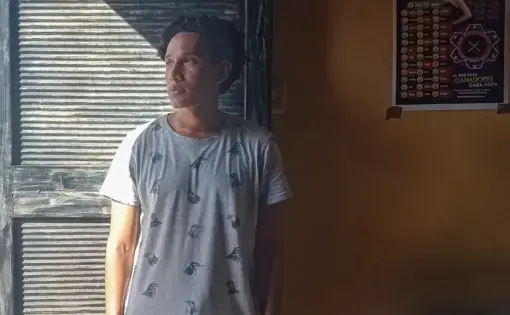 A patient stands near a doorway, his face half illuminated by sunlight.