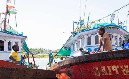 Two men on separate boats speak with each other