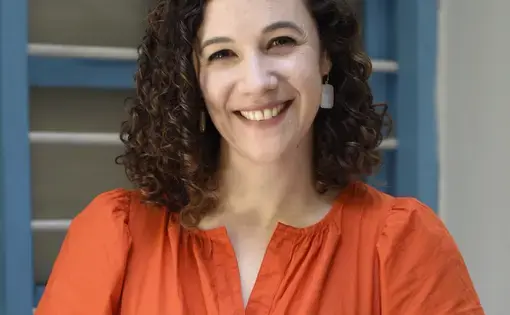 A woman in a bright orange dress with curly hair.