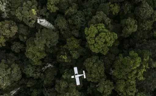 An aircraft flies over the Amazon rainforest.