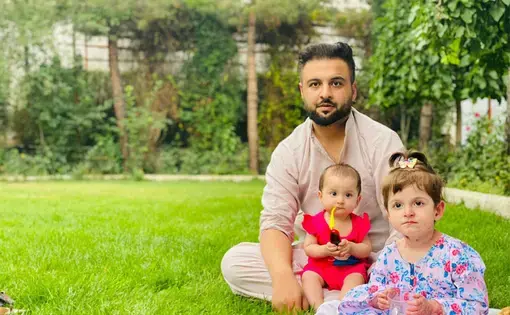 A father and his two daughters sit on the lawn