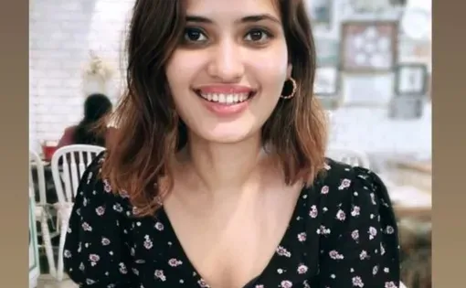 A woman with long dark hair wearing a black shirt smiles at the camera