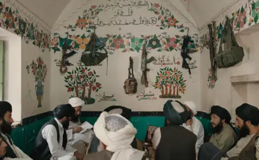 Thumbnail from video showing a group of men gathered in a room with white painted walls