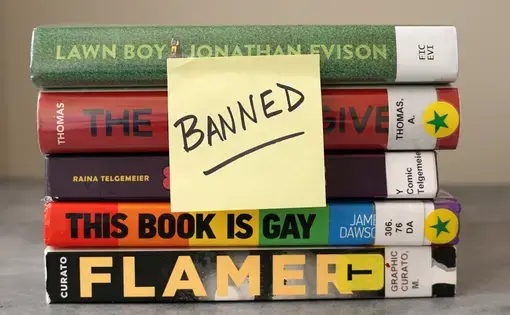 A post-it reading BANNED is affixed to a stack of library books.