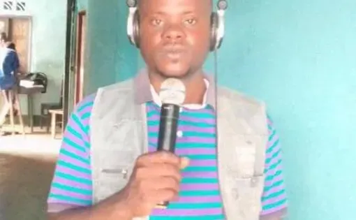 A man wearing headphone is holding a mic.