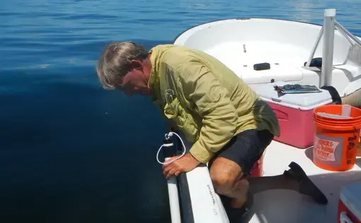 a man uses a water measurement tool off a boat
