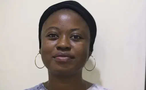 A woman with dark skin and dark hair wearing hoop earrings and red and blue shirt.