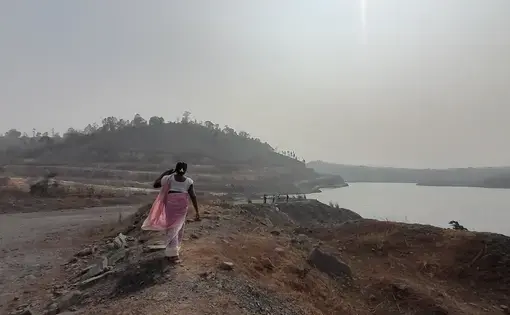 a woman walks along a shoreline, India
