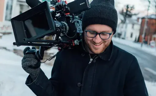 Will N. Miller walks down a snowy sidewalk with his video camera.