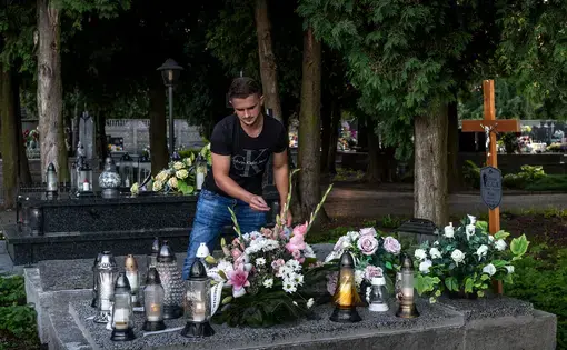 A man places flowers at a grave