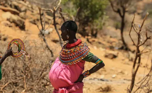 pregnant woman in traditional dress stands with hands on hips, Kenya