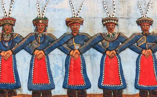 Pintung county, Taiwan - February 19,2015: Carving at the Taiwan Indigenous People Cultural Park depicting aboriginal Taiwanese people dancing in traditional attire in Pintung county, Taiwan. The men are wearing blue attire and are standing with inter-locking arms.