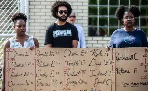 Protestors hold a sign listing individuals who died in prisons