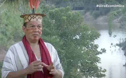 An indigenous man wearing traditional attire is deep in conversation.