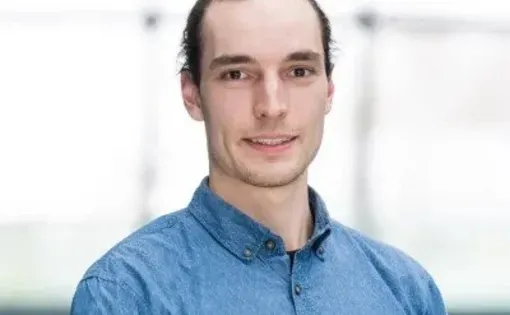 A man with dark hair wearing a blue button-down