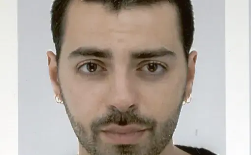 A man with short dark hair wearing a black and white shirt