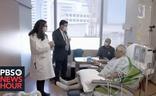 A doctor consults with a patient in a hospital room
