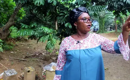 A woman in blue and pink shirt points to her right.