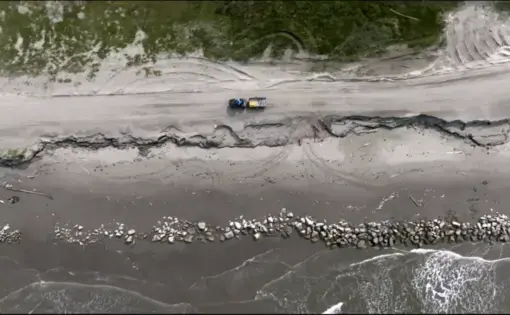 Overhead photo of a truck driving along an Alaskan island coast