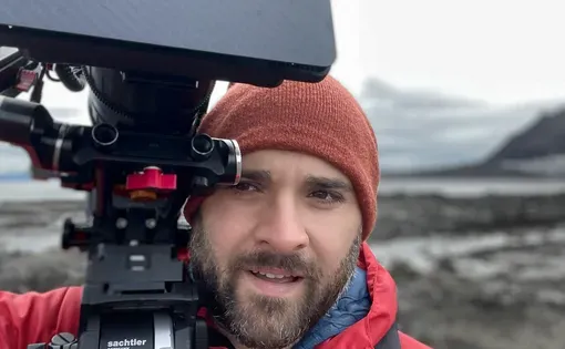Man wearing a red coat and red hat holding a large camera