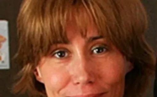 A woman with short red hair and bangs wearing sunglasses on her head