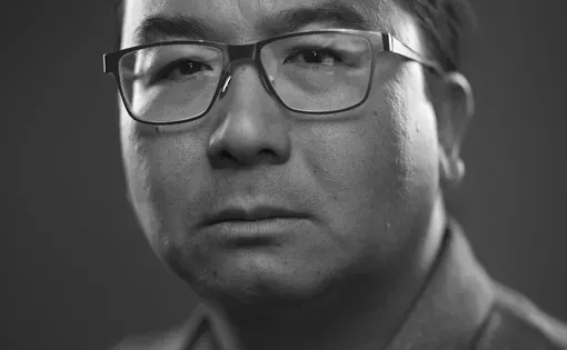 Black and white headshot of a man with glasses wearing a button down shirt