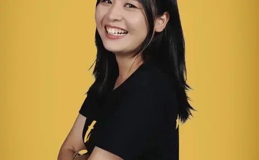 Ploythida beams at the camera with her arms folded.